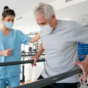Physical therapy aide helping a old man